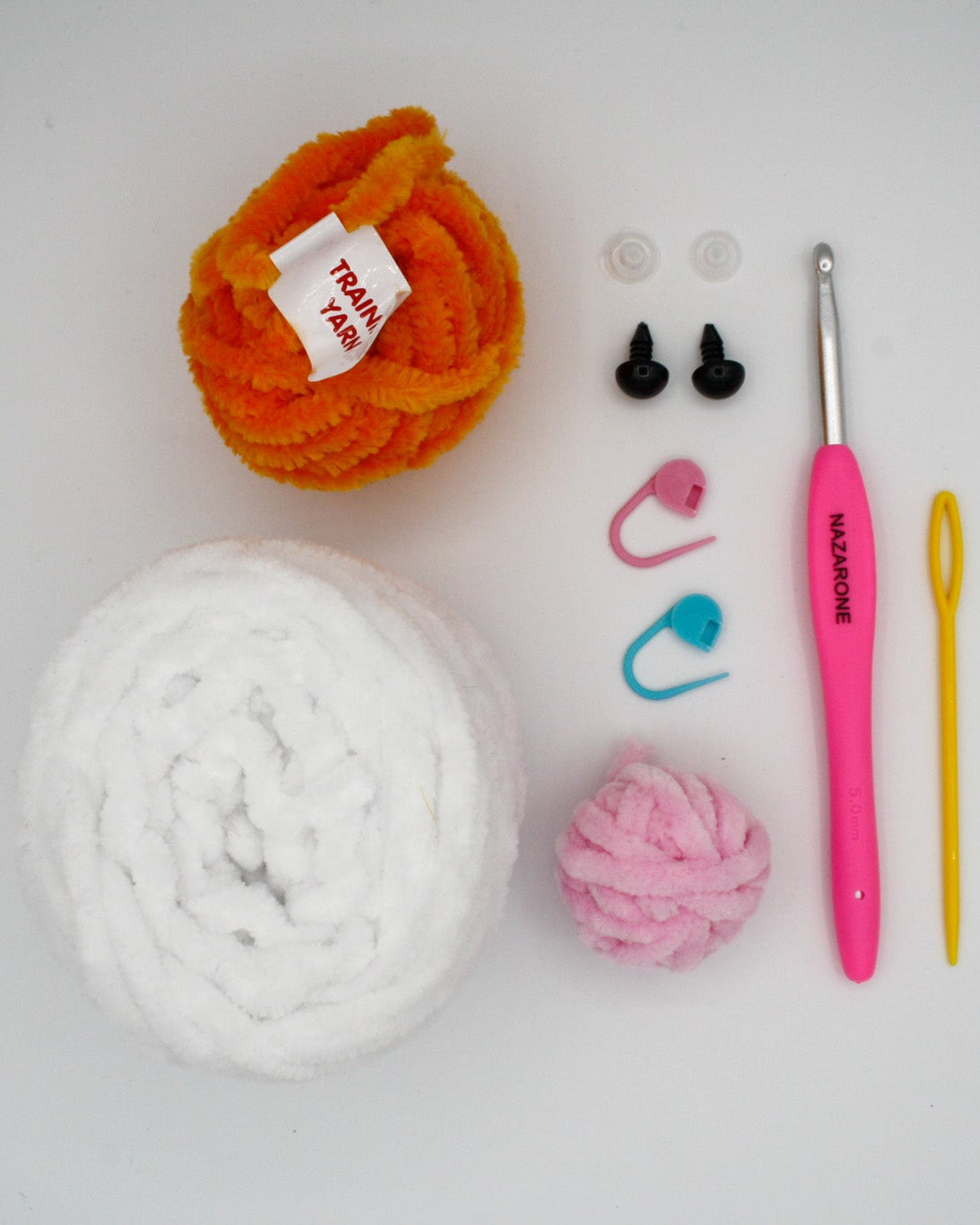 beginner crochet kit Bella the bunny materials including training yarn, chenille yarn for bunny, stitch markers, safety eyes, darning needle, and crochet hook.