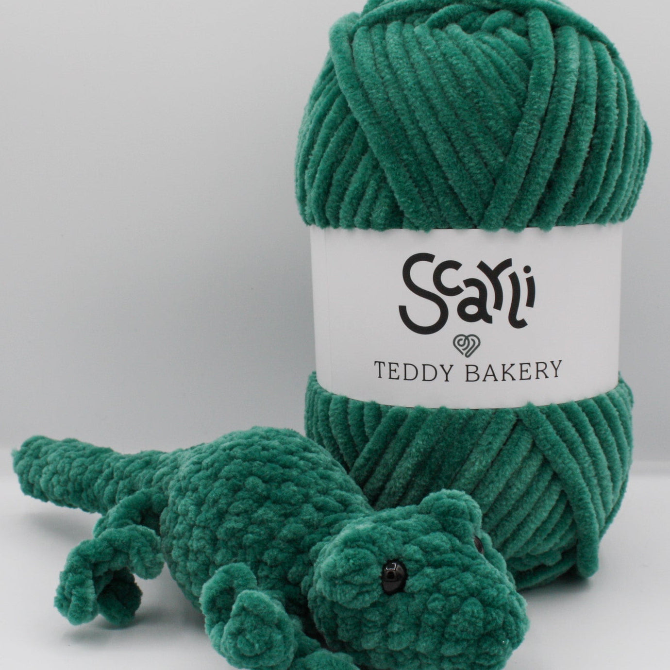 skein of pink green chenille plush yarn with amigurumi crochet gecko plushie