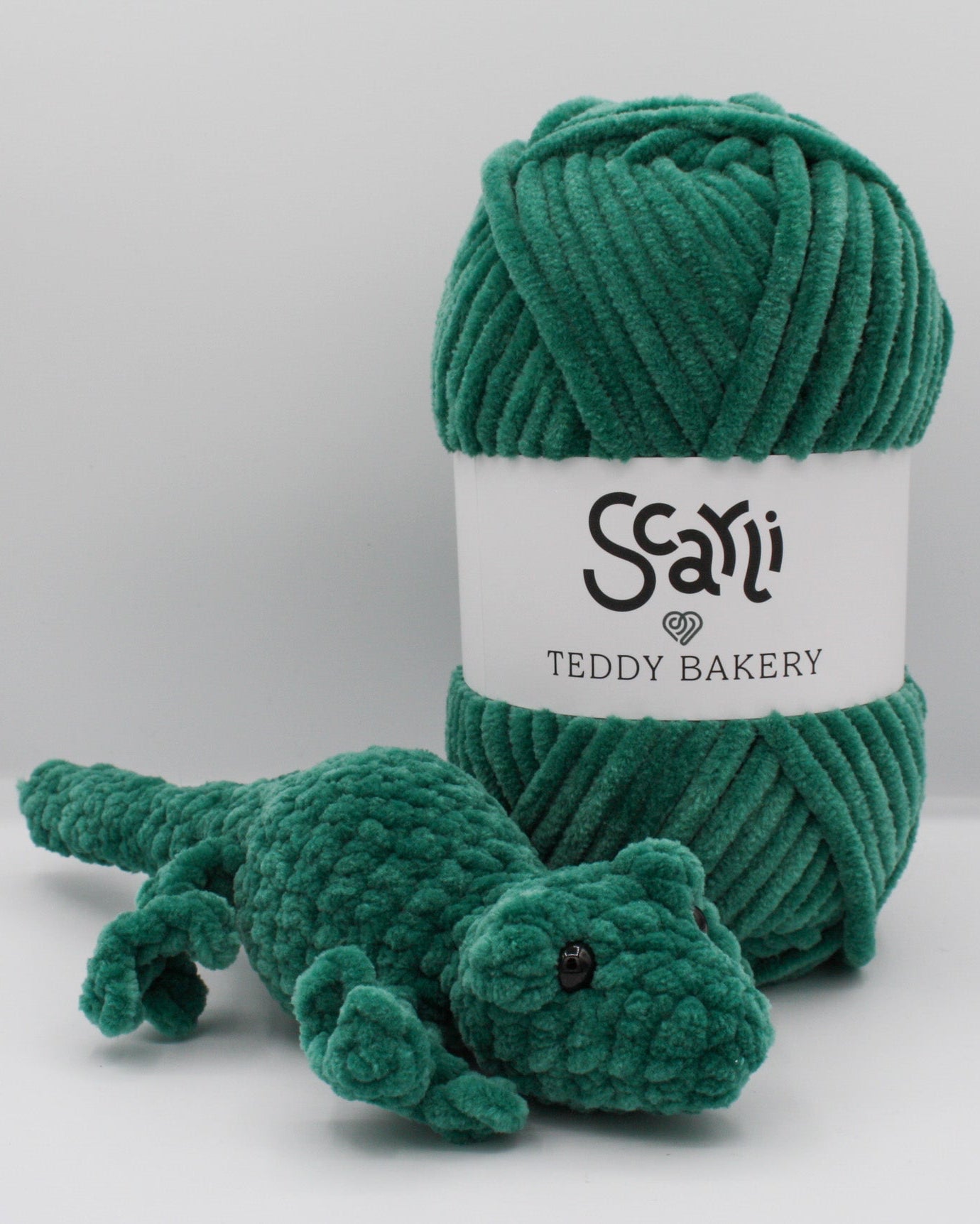 skein of pink green chenille plush yarn with amigurumi crochet gecko plushie