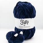 skein of navy blue chenille plush yarn and amigurumi crochet triceratops plushie